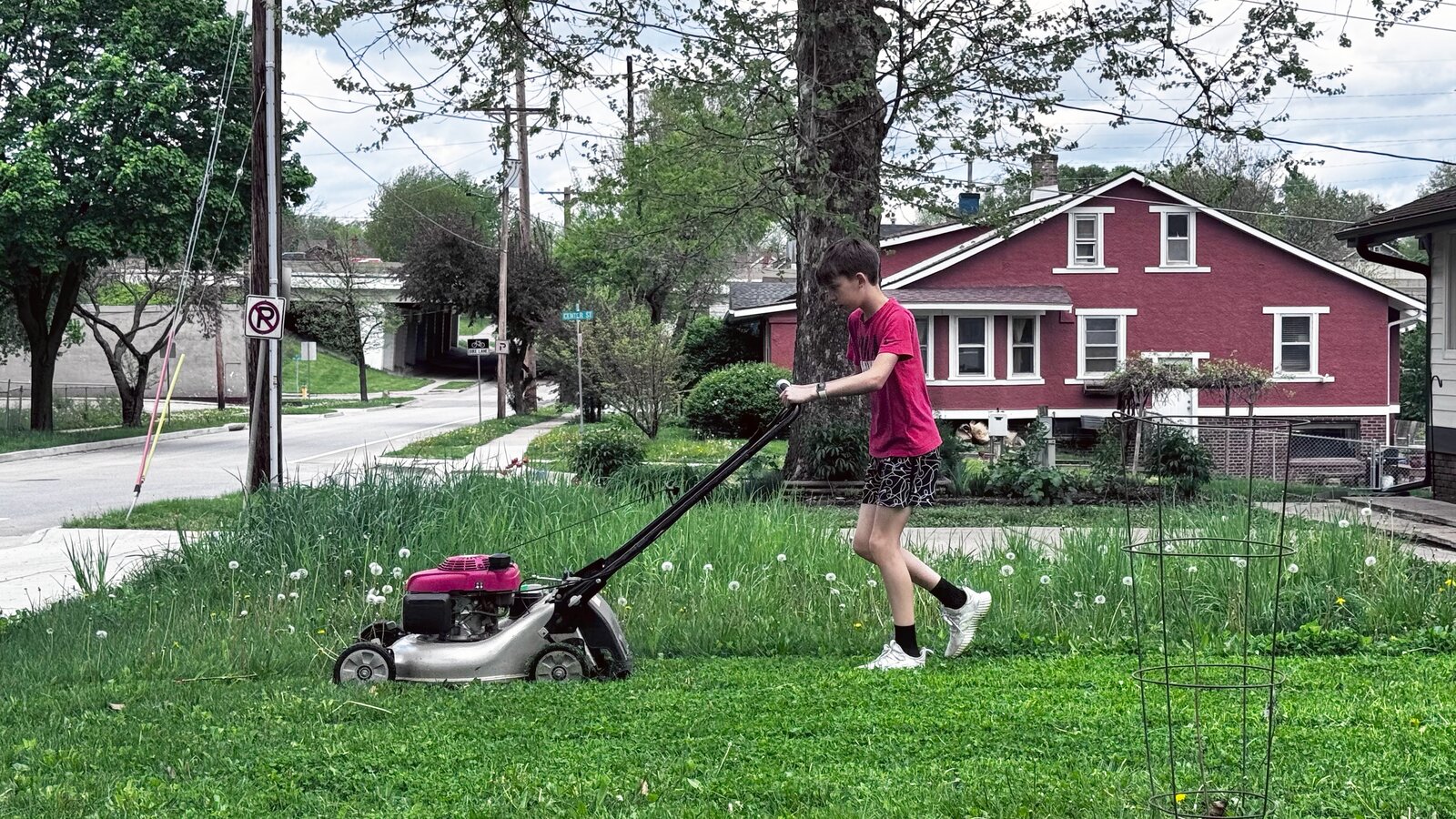 Stanley Hill mowing a front yard with a push mower in Des Moines